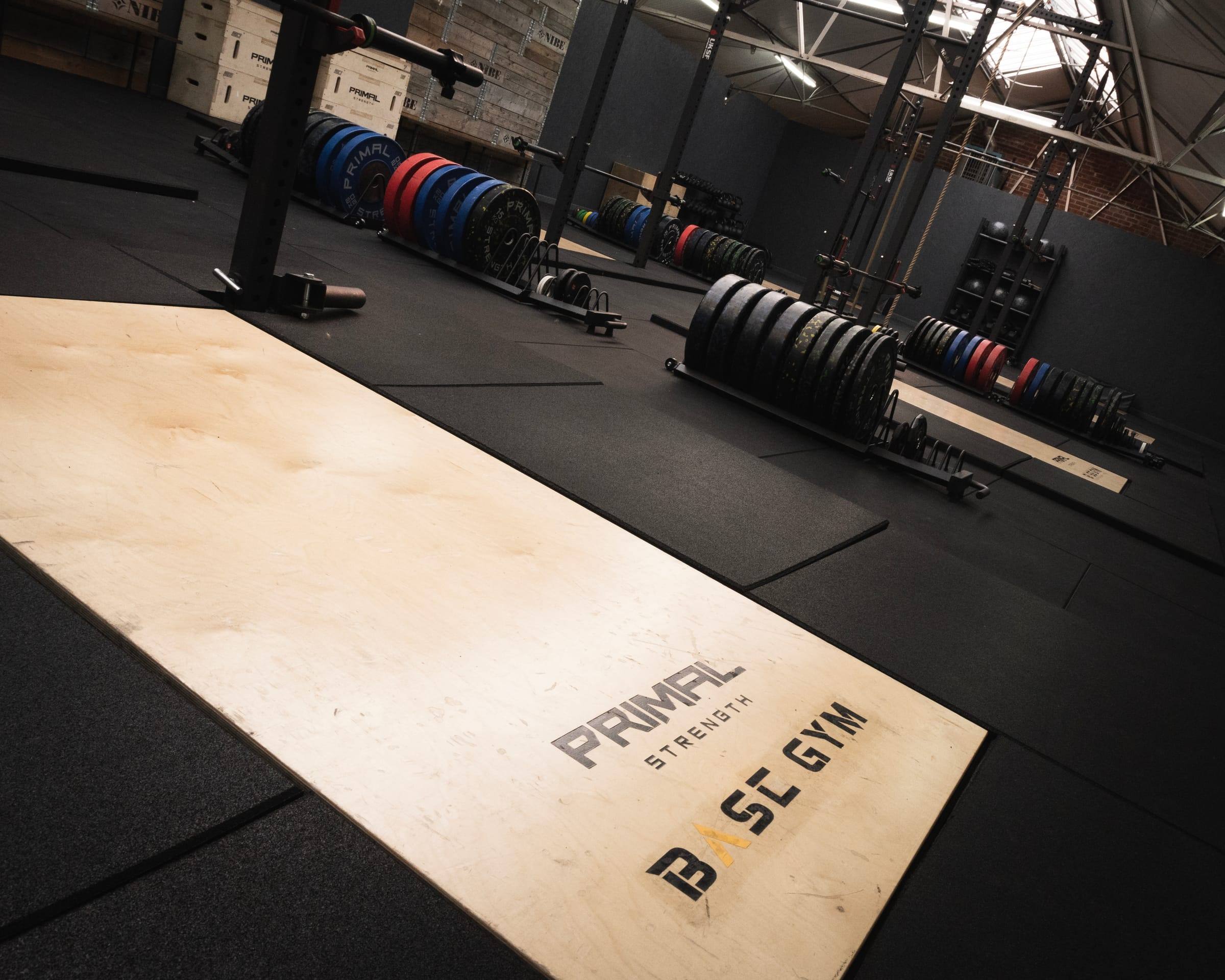 Base Gym branded lifting platform with barbells and plates beyond