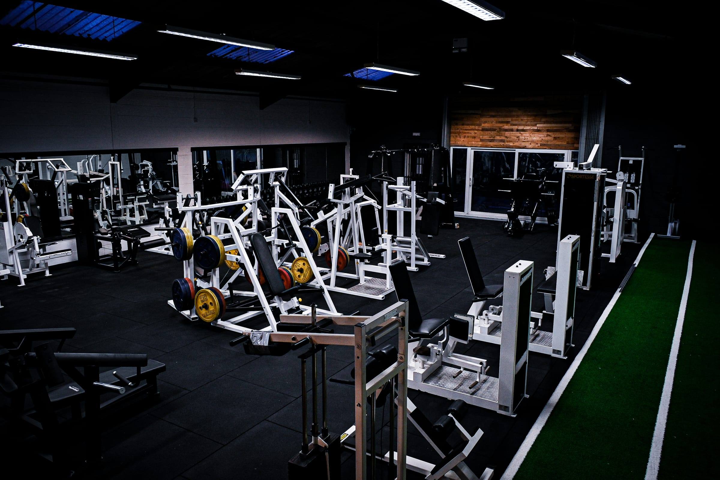 White plate-loaded machines beside the turf sprint track at Base Gym Yeovil