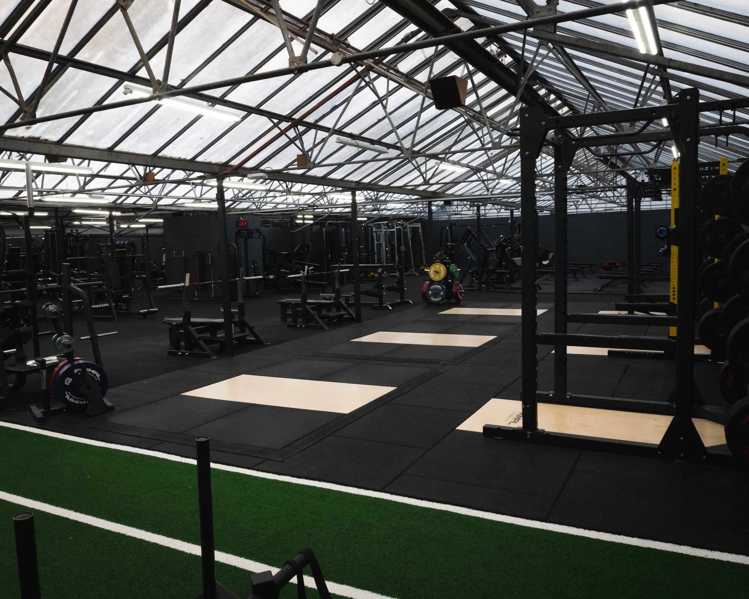 Power racks and platforms lining the Bristol gym under the steel roof trusses