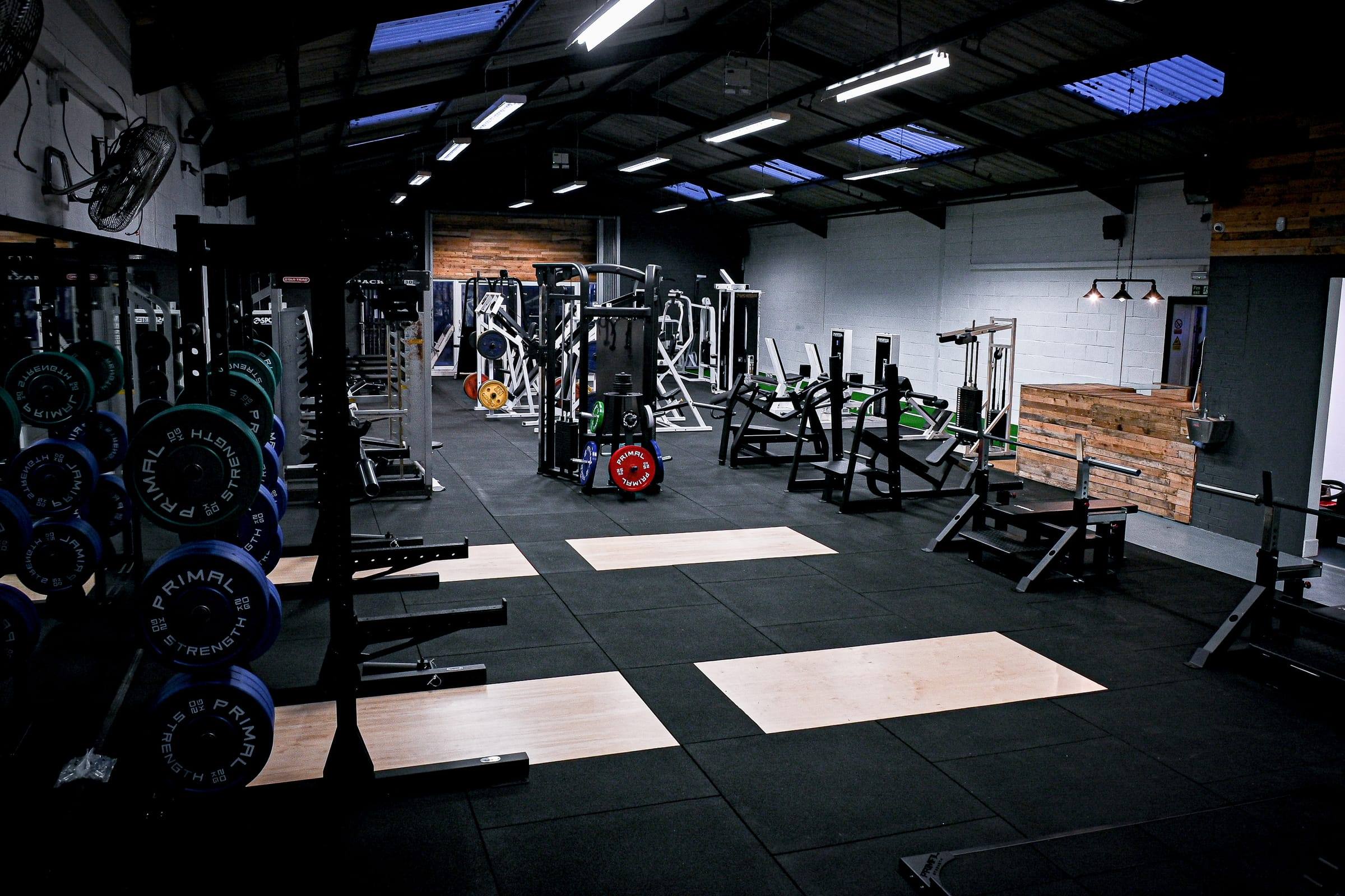 Base Gym Yeovil: lifting platforms with racked bumper plates and plate-loaded machines behind