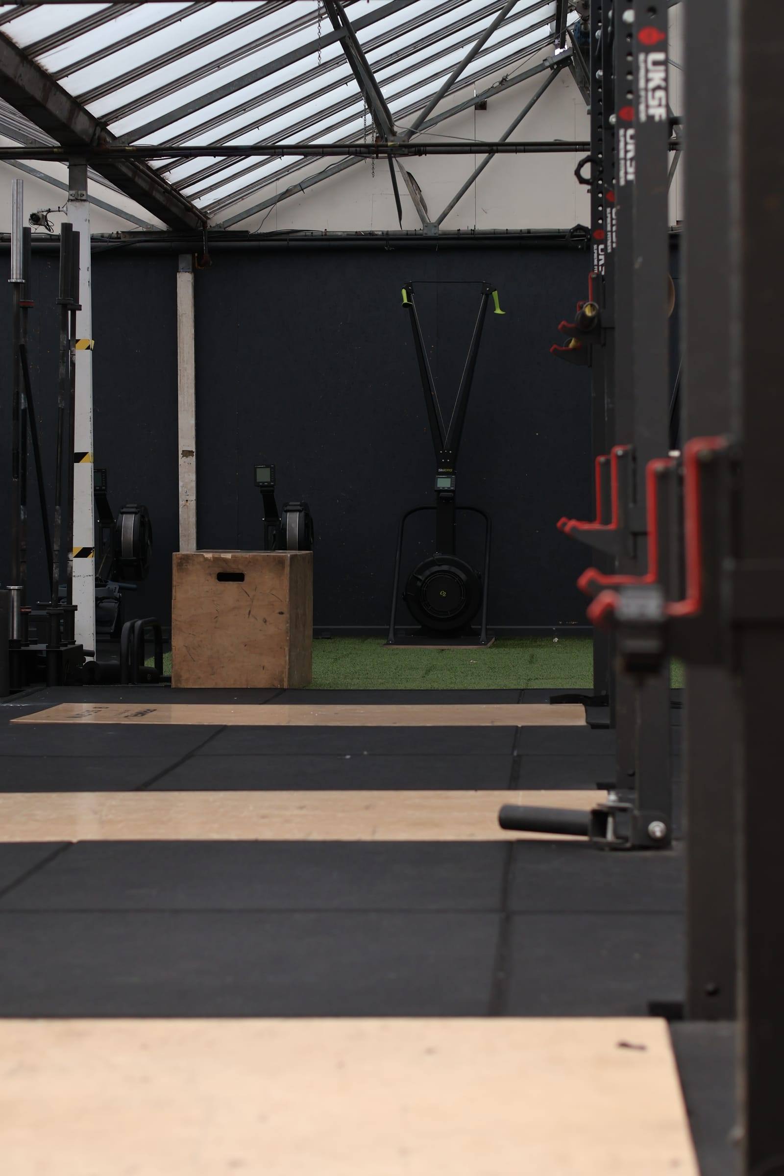 Looking through a power rack towards a plyo box and turf at Base Gym Bristol